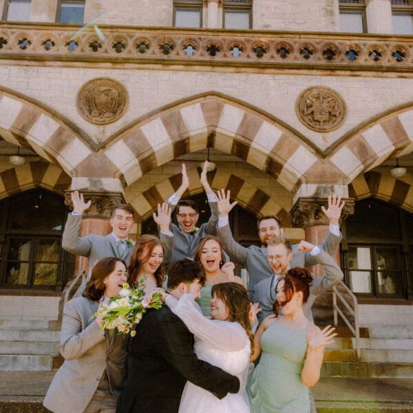 bride and groom embracing surrounded by cheering wedding party