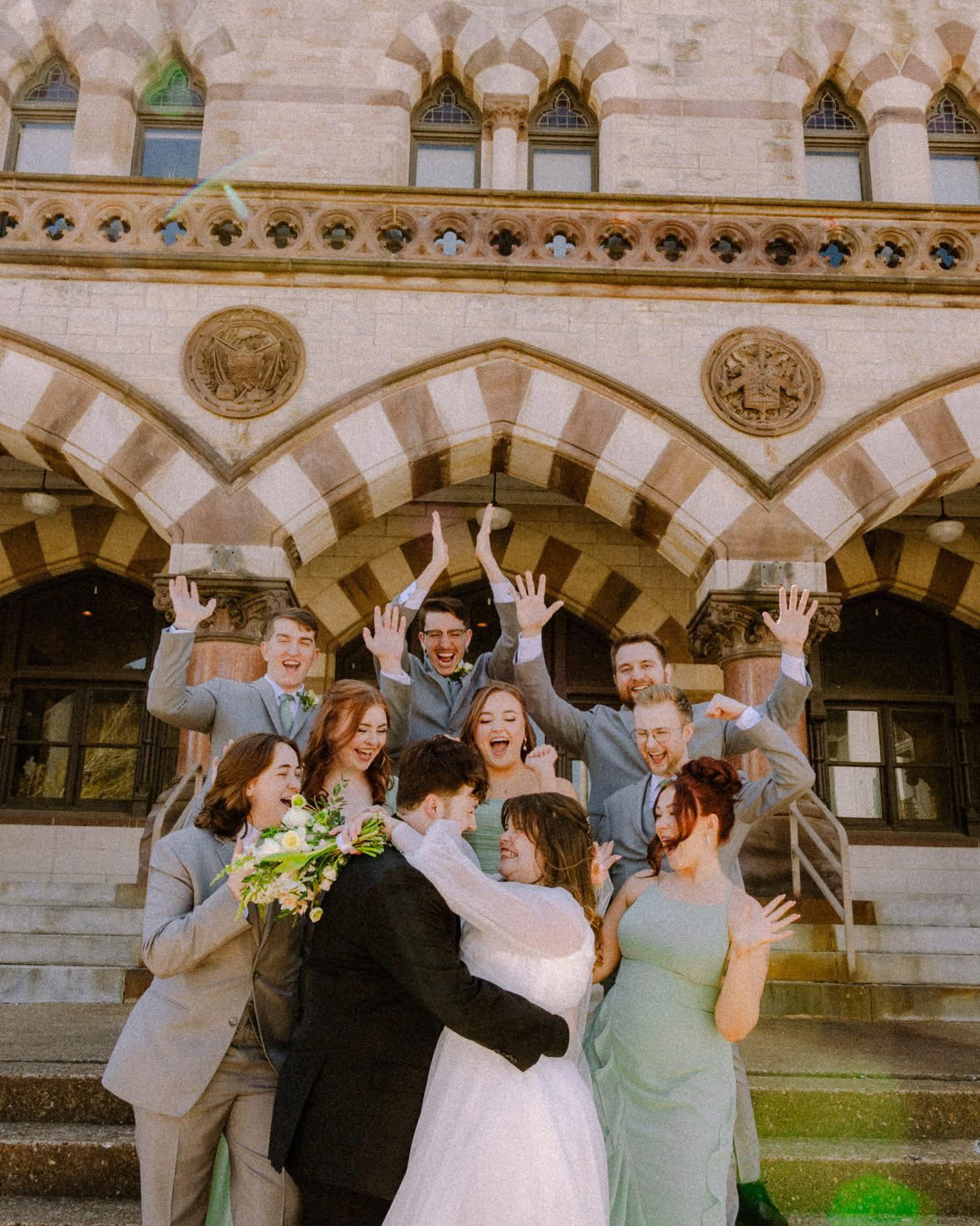 bride and groom embracing surrounded by cheering wedding party